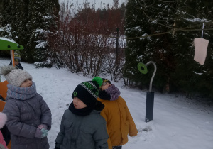 dzieci szukają i obserwują ptaki w ogrodzie przedszkolnym